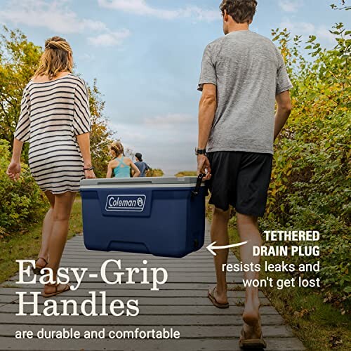 People carrying a Coleman cooler with easy-grip handles on a boardwalk.