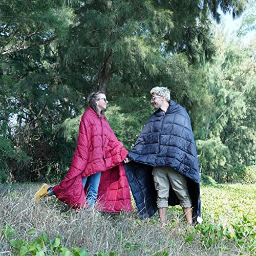 Couple standing outdoors wrapped in blankets.