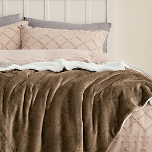 Cozy brown fleece blanket on a bed with decorative pillows.