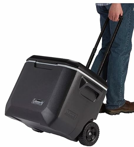 Person pulling a black rolling cooler