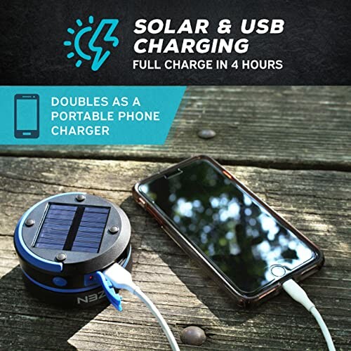 Solar and USB portable phone charger with phone on a wooden surface.