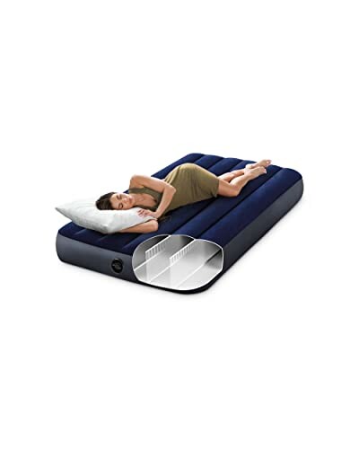 Woman sleeping on a blue air mattress with internal structure visible.